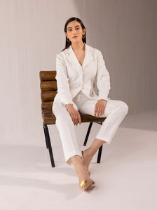 Elegant woman in off-white suit sitting on a chair.