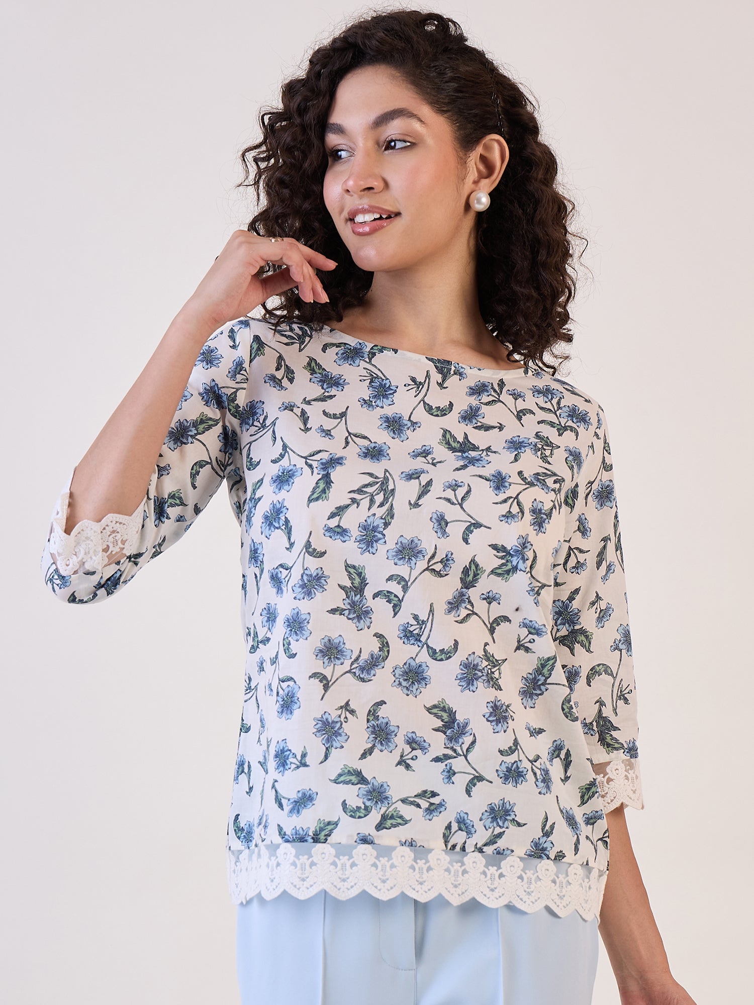 White floral boat neck top with lace trim and three-quarter sleeves.