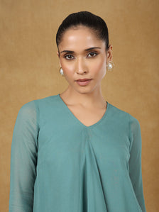 Model wearing a stylish green A-line top on a gold background.