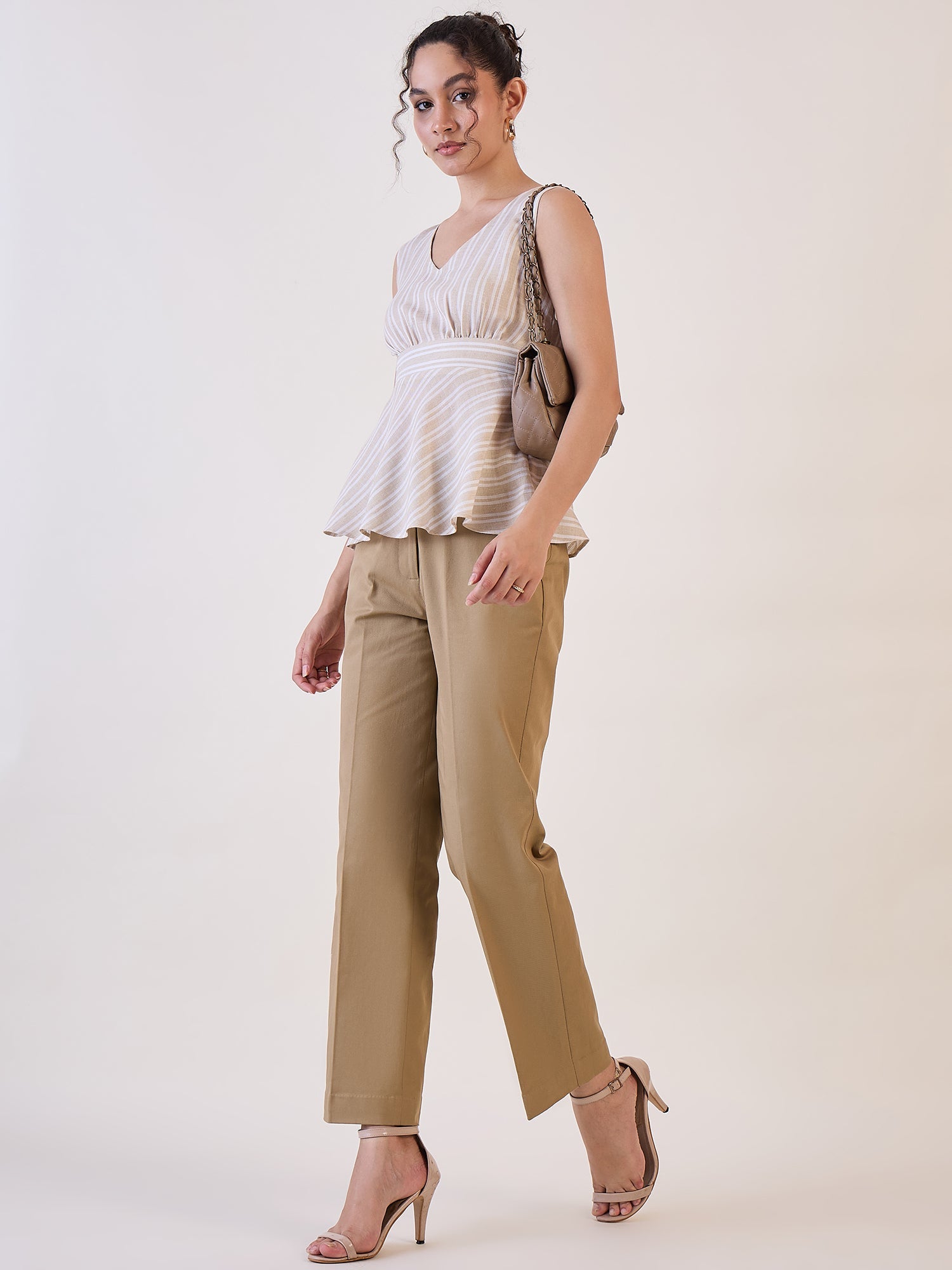 Stylish woman wearing camel brown straight fit mid-waist trousers.